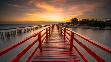 Fototapeta na wymiar Red bridge in the evening with a beautiful sunset, Dolphin viewpoint, Samut Sakhon, Thailand.