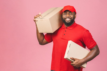 Delivery concept. African american delivery black man carrying parcel isolated over pink background.
