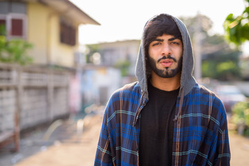 Young handsome bearded Indian hipster man in the city streets