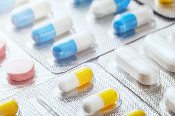 pile of medical pills  in red, blue and yellow colors in  silver plastic packaging