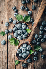 Blueberries in wooden spoon on old wood background. Healthy eating and nutrition concept.