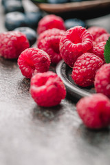 Freshly picked raspberries in bowl on old metal background. Healthy eating and nutrition.