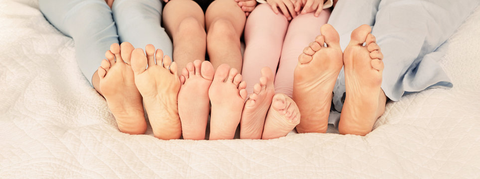 Many bare feet of a family in bed