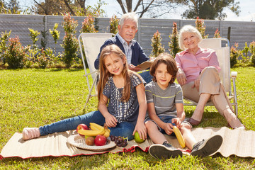 Grandparents and grandchildren are having a picnic in the garden