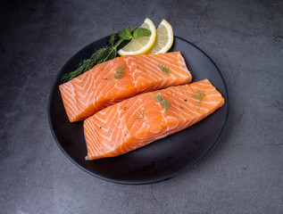 Raw salmon filet with rosemary and lime on dark slate background, wild Atlantic fish. Delicious fish meat. top view