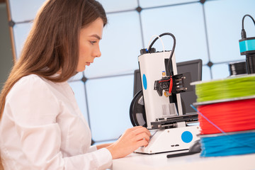 Young female designer working on a prototype device on a 3D printer