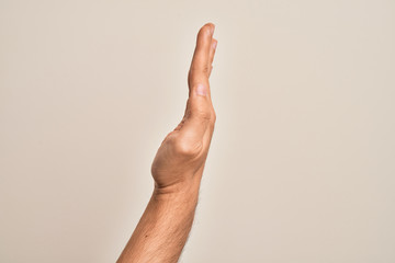 Hand of caucasian young man showing fingers over isolated white background showing the side of stretched hand, pushing and doing stop gesture
