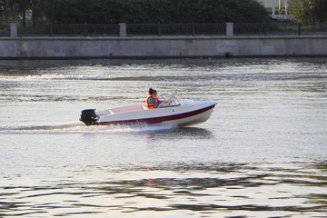 One non-registrated 9.9 hp plastic outboard motor boat with two passengers in life jackets floats...