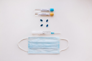 Top view desk in hospital with Coronavirus test tubes with patients blood, pills and respiratory mask.