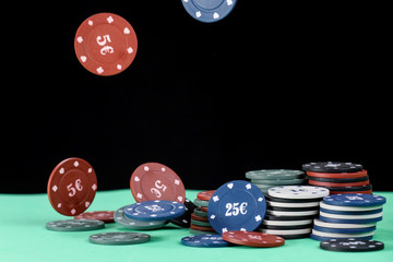 Poker playing chips on a green table and black background. Online gambling. Addiction. Falling poker chips