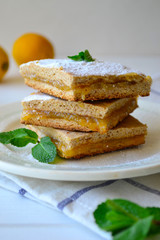 Sweet homemade thin whole-grain lemon pie cut in squares, covered with powdered sugar and decorated with fresh mint.