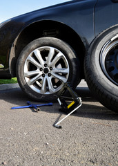 Tire change with spare tire and aluminum rim following a puncture, with a lug wrench and jack