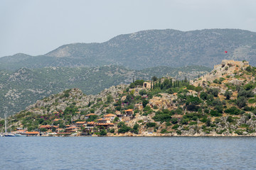 Kalekoy village with stone built houses and castle on top of hill in Uchagiz bay in Turkey