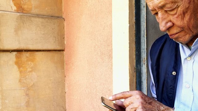 Woman delivering food in paper bag during Covid 19 outbreak. Feme volunteer holding groceries in the house porch. Female volunteer helping disabled old man use smartphone. Food box donation. Social he