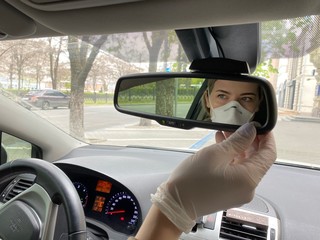 girl in a protective mask looks in the mirror in a car. During quarantine- coronavirus.  Covid-19.