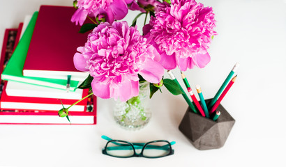books, glasses, pencils, notebook and pink peonies flowers, distance education background at home during the pandemic. The quarantine, stay home, work from home concept stop coronavirus COVID-19ю