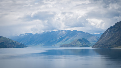 Fototapeta na wymiar Scenic alpine lake surrounded by mountains shot on sunny day. Location is lake Hawea, New Zealand