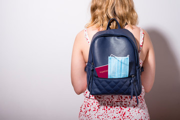 Female backpacker with a mask and passport in her backpack. Travel concept with covid 19. Copy...