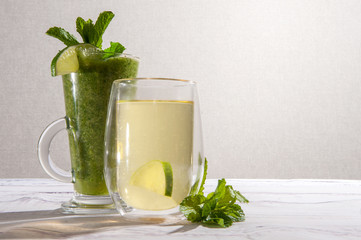 Healthy blended smoothie from salad, mint, celery, avocado, cucumber.  Green tea in double sided glass