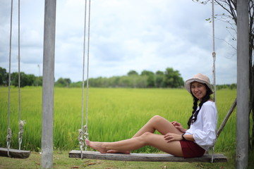Naklejka premium Woman sitting on a swing in a rice field Rayong, Thailand
