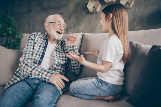 Photo of two people old grey haired grandpa little granddaughter sitting comfort sofa telling news secrets stay home house quarantine safety modern design living room indoors