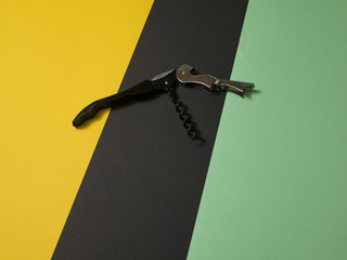 Black multi purpose tool with corkscrew bottle opener isolated on colored background.