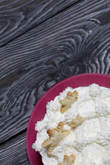 Cake decorated with cream cream. On top of the decoration in the form of snowflakes. Located on brushed pine boards painted black.