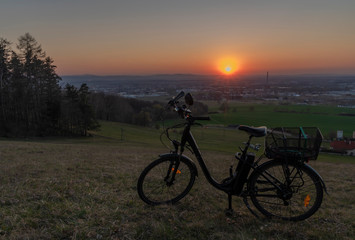 Black electric bike on ski slope in Budweis city with sunset