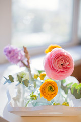 Beautiful colorful flowers in a glass bottles on a vintage wooden tray.