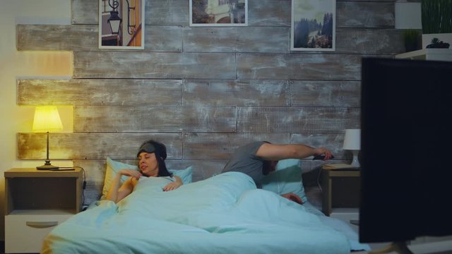 Tired couple in their bedroom going to sleep and turing the lamp off.