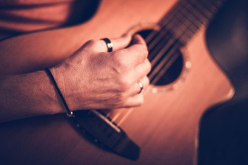 Male Musician Playing On Acoustic Guitar While Sitting Down.