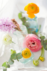 Beautiful colorful flowers in a glass bottles on a vintage wooden tray.