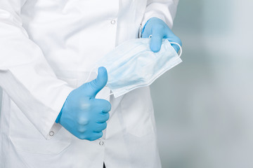 close up of doctor's hand with a medical face mask for virus protection showing thumbs up