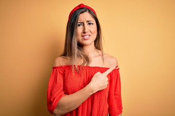 Young beautiful woman colorful summer style over yellow isolated background Pointing aside worried and nervous with forefinger, concerned and surprised expression