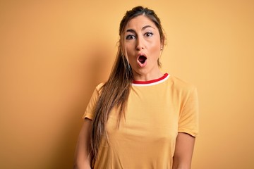 Young beautiful athletic woman wearing casual t-shirt and ponytail over yellow background afraid and shocked with surprise expression, fear and excited face.