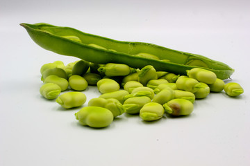  open green broad beans in their shells and some shelled beans isolated on a white background