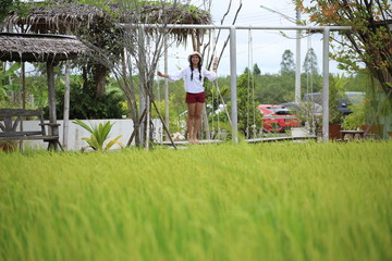 A woman standing on a swing in a rice field Rayong, Thailand