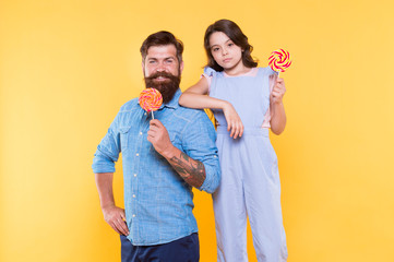 Obraz premium When children seem hard to please. Daughter and father eat sweet candy. Bearded man and cute sweet baby. Loving daddy and small girl eating lollipop. Summer vacation. Happy holidays. Sweet childhood