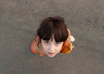 A little girl with blue eyes stands and looks up.