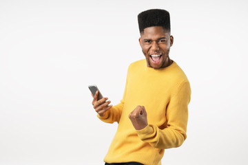 Portrait of excited young man with mobile phone isolated over white background and celebrating