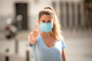 girl makes a positive gesture with the medicinal mask