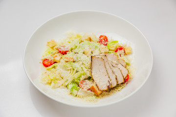 Classic caesar salad with chicken on a white plate