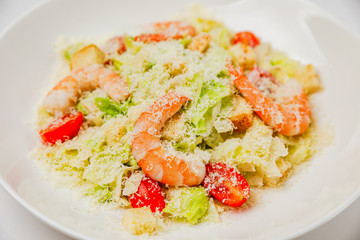 Caesar salad with prawns on a white plate, a close-up photo