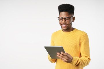 Smiling african guy using tablet digital isolated on white studio background