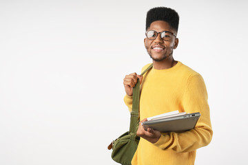 Happy college student in eyeglasses with backpack holding laptop isolated on white background