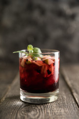 Old fashioned cocktail with blackberry liqueur and apple slices on rustic background. Selective focus. Shallow depth of field.