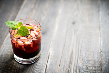 Old fashioned cocktail with blackberry liqueur and apple slices on rustic background. Selective focus. Shallow depth of field.