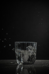 Transparent glass with splash of water on dark background