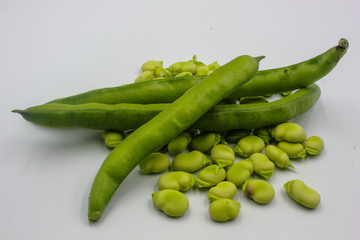 panoramic of open green broad beans in their shells and some shelled beans isolated on a white background
