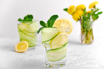 Concept summer refreshing drink of water, cucumber slices, lemon and mint in a high key